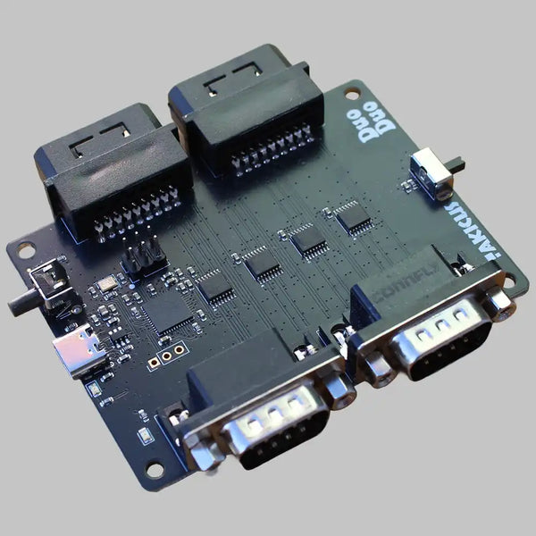 A black circuit board featuring multiple connectors, including two 9-pin D-sub connectors, two multi-pin female headers, a USB-C port, and a small toggle switch.